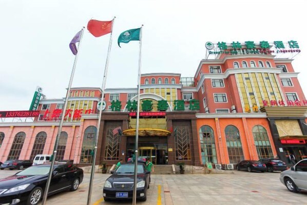 Un hotel de estilo arquitectónico tradicional, con varias banderas, una entrada destacada y un área de estacionamiento.