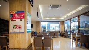 A spacious indoor dining area with multiple tables and chairs, a large pillar with a poster, and large windows allowing natural light. - GreenTree Inn Jiangsu Wuxi Jiangyin Yunting Changshan Avenue Chengyang Road Business Hotel (Jiangyin)