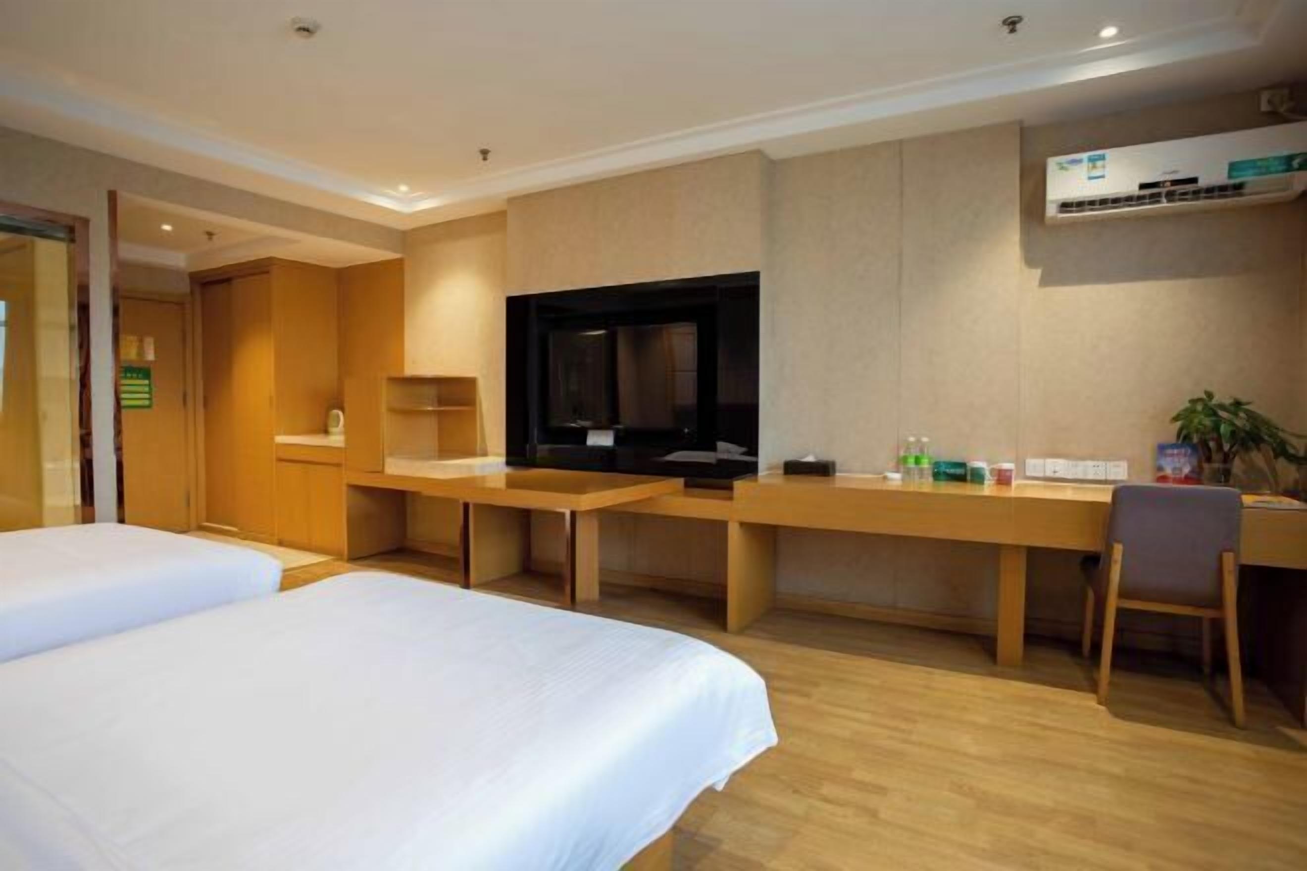 Een hotelkamer met twee bedden, een bureau, een televisietoestel en een airconditioning.