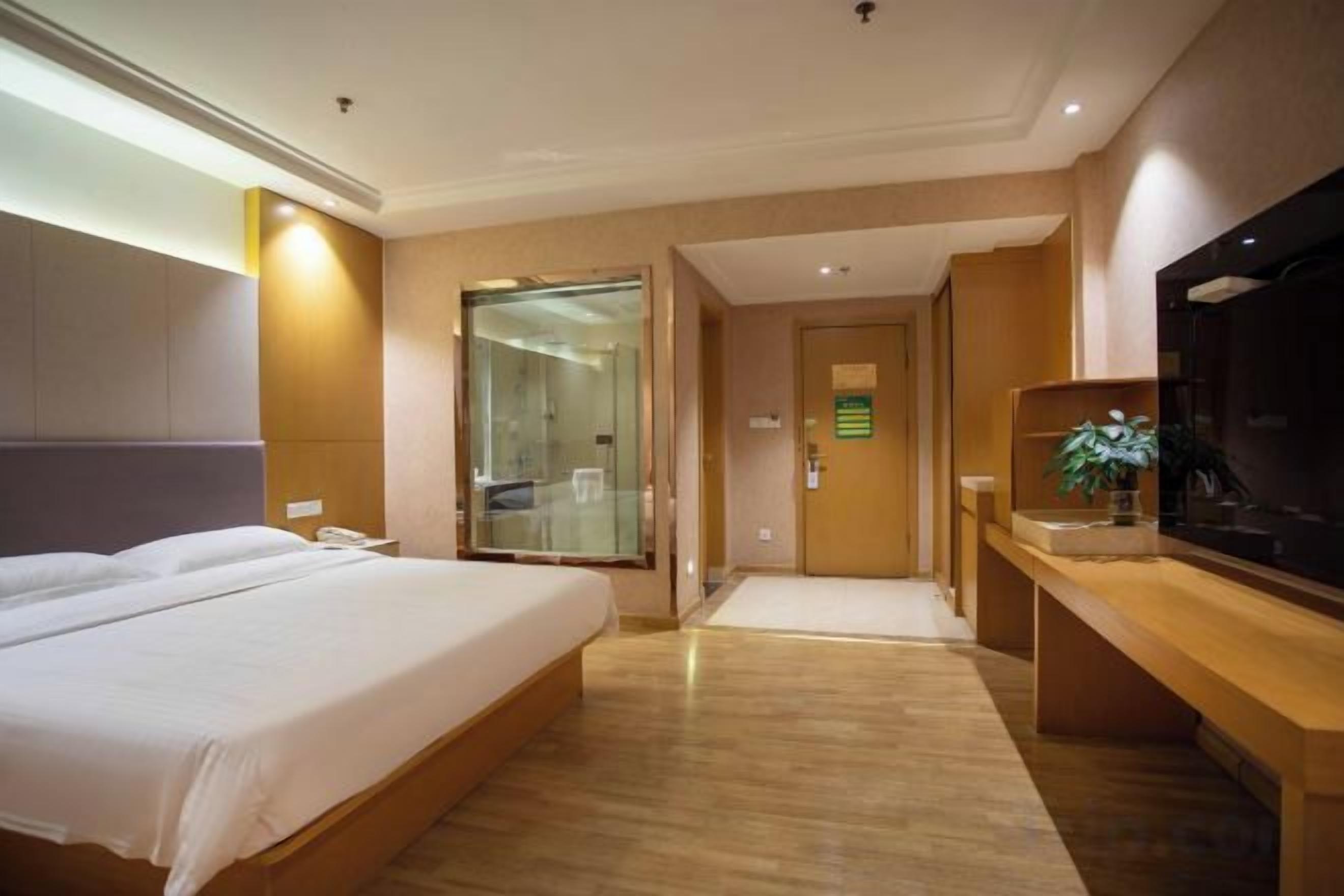 A hotel room with a bed, a TV, and a desk.