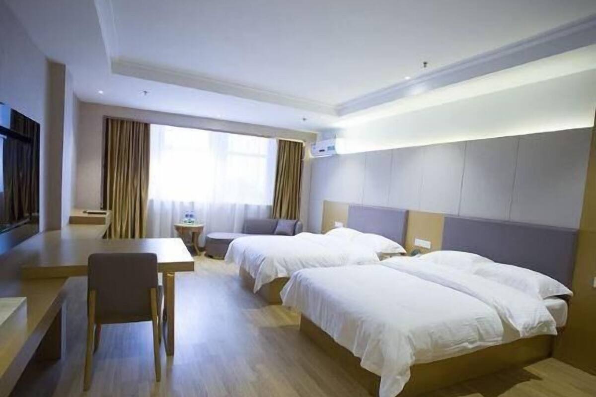 Et hotelværelse med to senge, et skrivebord, en stol og et fjernsyn.
