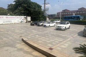 Een parkeerplaats met meerdere auto's, een bus en een gebouw op de achtergrond.