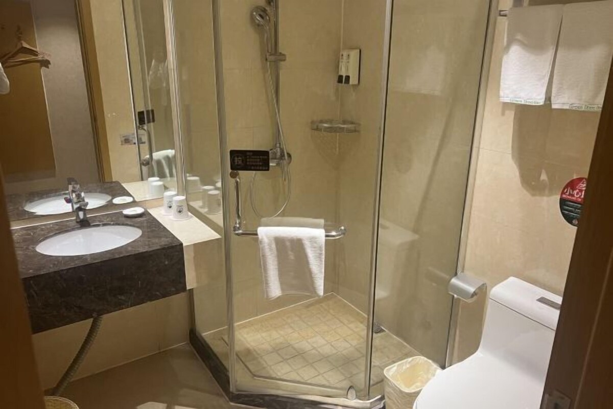 A modern bathroom with a glass-enclosed shower, a sink with a marble countertop, and a toilet.