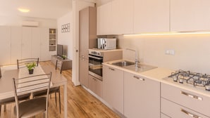 A modern kitchen with a dining area, featuring a stove, sink, and oven.