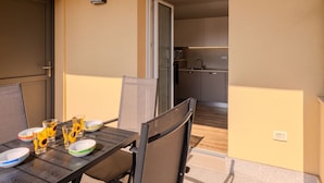 A dining area with a table set for four, chairs, and a view into a kitchen.