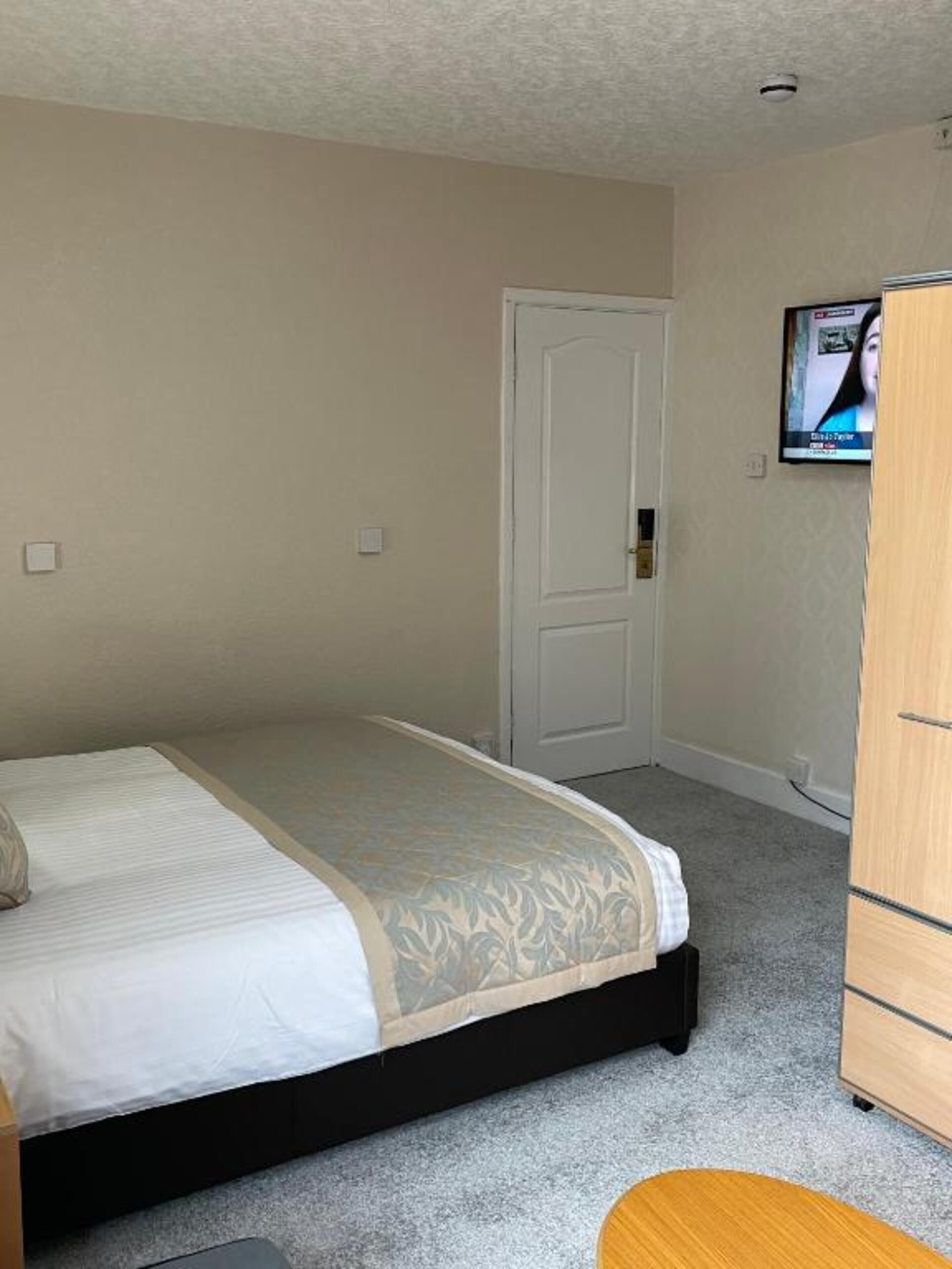 A bedroom with a bed, a wardrobe, and a television on the wall.