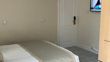 A bedroom with a bed, a wardrobe, and a television on the wall.