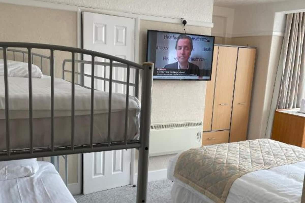 A hotel room with bunk beds, a television, a wardrobe, and a window with curtains.