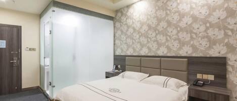 Quarto de hotel com cama, mesas de cabeceira, guarda-roupa e parede com padrão floral.
