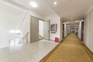 A hotel hallway with a carpeted floor, a staircase, and fire extinguishers. - Huijia Express Hotel (Luoyang)