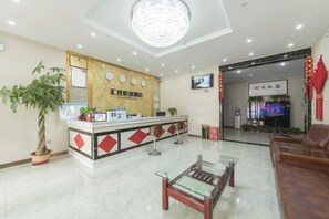 A hotel reception area with a reception desk, a chandelier, a television, and a seating area. - Huijia Express Hotel (Luoyang)