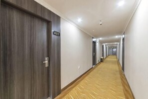 A hotel corridor with wooden doors, a carpeted floor, and a sign indicating room number 402. - Huijia Express Hotel (Luoyang)