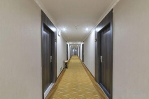 A hotel corridor with doors on both sides, a patterned carpet, and a ceiling with recessed lighting. - Huijia Express Hotel (Luoyang)