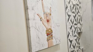 Ein Gemälde einer Hand mit Ringen an einer Wand.