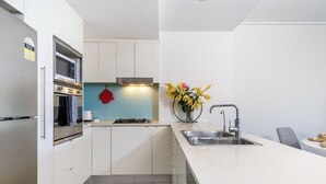 Una cocina moderna con armarios blancos, un lavamanos de acero inoxidable y una estufa a gas.