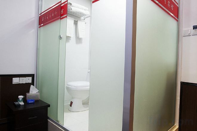 Een badkamer met een toilet, een spiegel en een wastafel met een pak tissues.