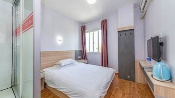 Een hotelkamer met een bed, nachtkastje, televisie en een raam met gordijnen.