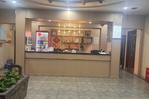 A reception desk with a vending machine, a counter with a computer, and a wall-mounted phone. - Xinheng Hotel (Jinzun Road) (Shanghai)