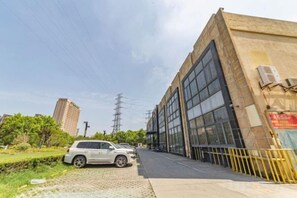 A building with large windows and a parked car on the street. - Xinheng Hotel (Jinzun Road) (Shanghai)