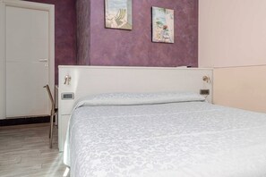 A bedroom with a bed, a door, and two paintings on the wall. - Hotel 3 Your Haven of Peace in Ventimiglia (Ventimiglia)