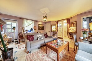 A cozy living room with a sofa, armchairs, a coffee table, and a dining area with a lamp. - Groves Hall Garden Apartment Sleights Near Whitby (Whitby)