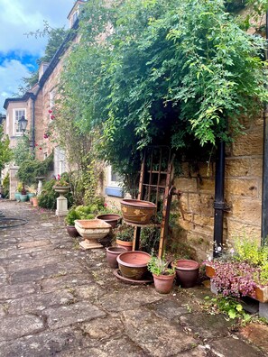 A stone-paved courtyard with terracotta pots and a wooden ladder leaning against a stone wall. - Groves Hall Garden Apartment Sleights Near Whitby (Whitby)