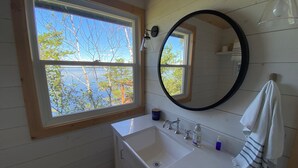 Un baño con ventana, lavabo, espejo y perchero.