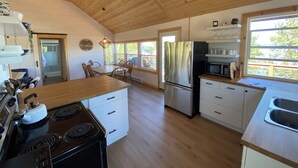 Una cocina amplia con pisos de madera, un refrigerador de acero inoxidable, una estufa y un comedor con sillas.