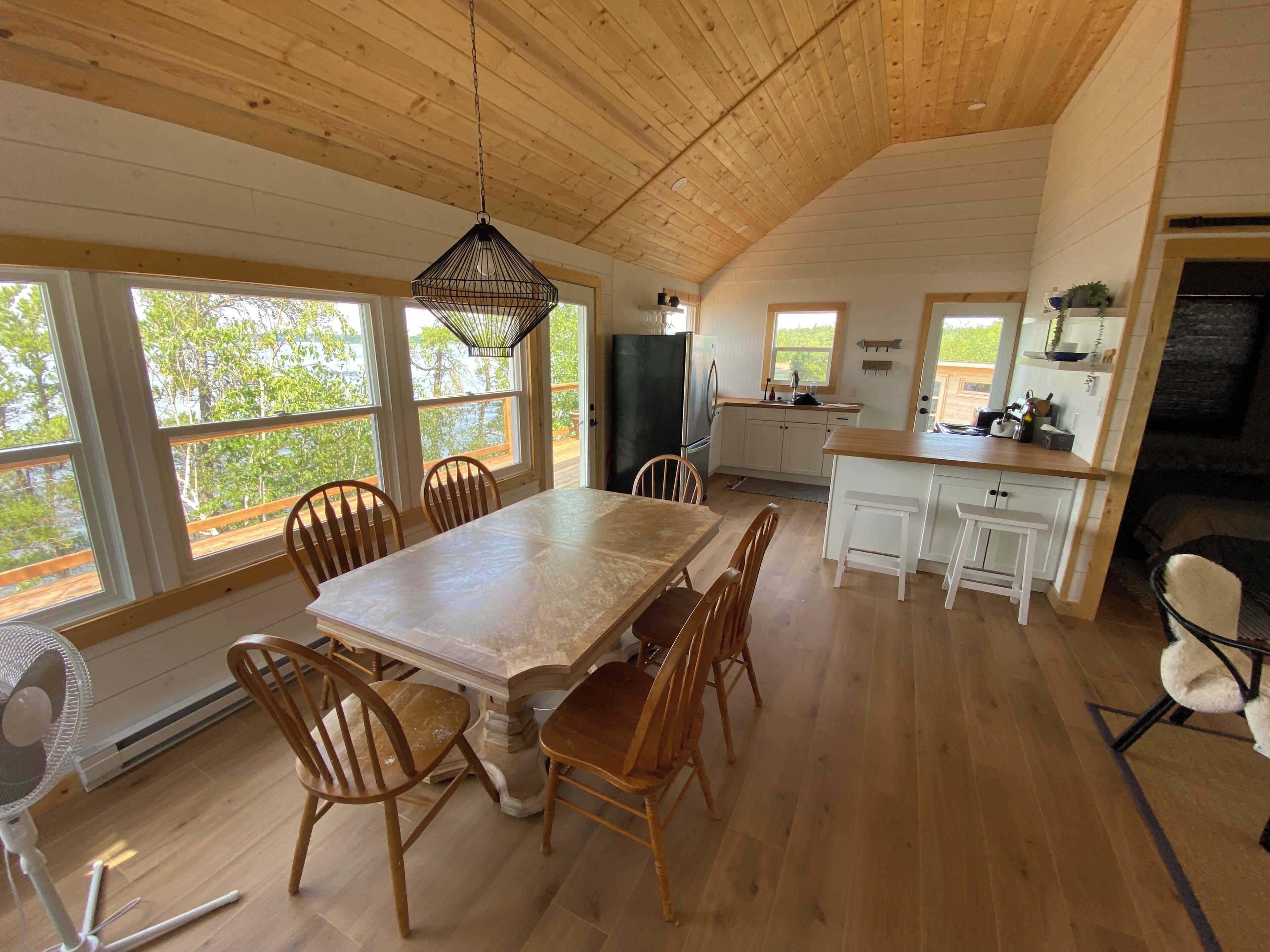 Une cuisine spacieuse dotée de meubles en bois, d’un grand îlot central et d’un coin repas avec des chaises en bois.