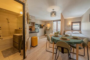 Un espace de vie compact comprenant une cuisine, un coin repas et une salle de bain séparée.