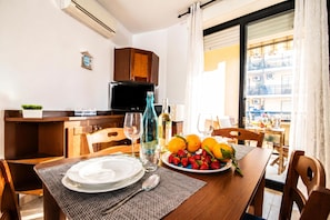 A dining area with a table set for two, a television, and a view of the outside.