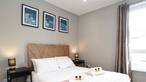 Una habitación de hotel con una cama grande, dos mesitas de noche y tres cuadros en la pared.