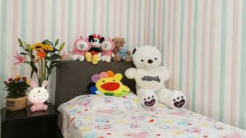 A bed with a colorful bedspread and a white teddy bear on it.