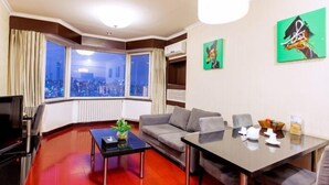 A modern hotel room with a city view, a sofa, a dining table, and artwork on the walls. - Beijing Champs-Elysees Hotel (Panjiayuan Shilihe Subway Station) (Beijing)