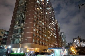 Ein Hochhaus mit mehreren Etagen, einem sichtbaren Eingang und einem Geschwindigkeitsbegrenzungsschild.