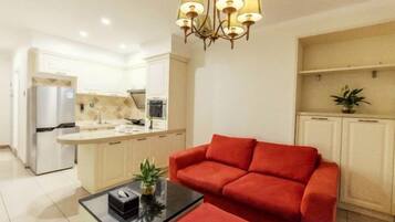 A modern living room with a red sofa, a coffee table, and a kitchen in the background.