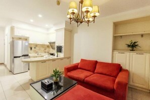 Una sala de estar moderna con un sofá rojo, una mesa de centro y una cocina al fondo.