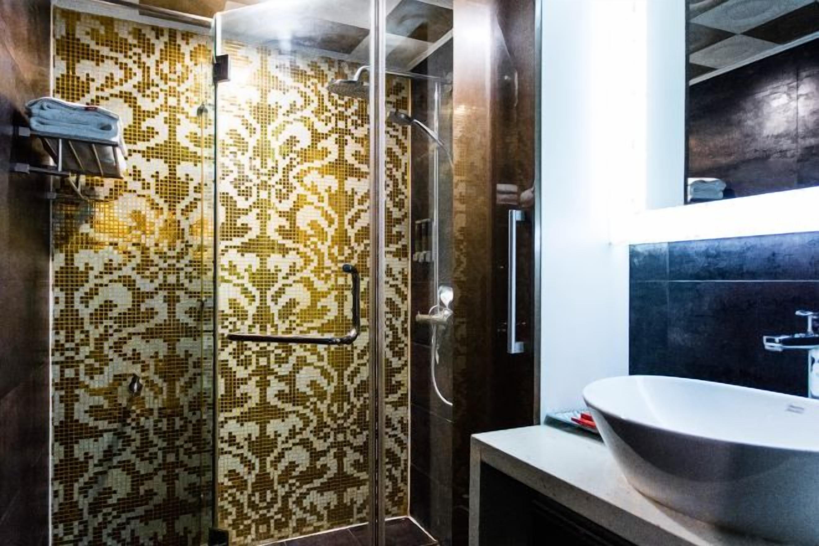 Ein Badezimmer mit Duschabtrennung aus Glas, einem Waschbecken mit großzügiger Spüle und einem Spiegel darüber.