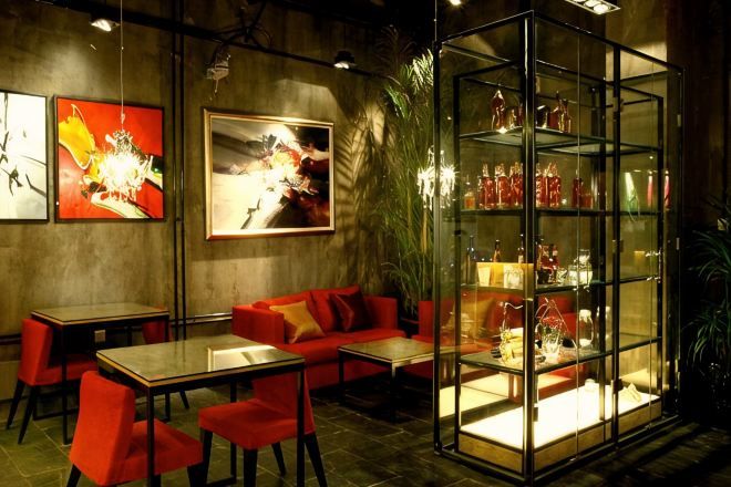 A restaurant with a glass display case, red seating, and artwork on the walls.