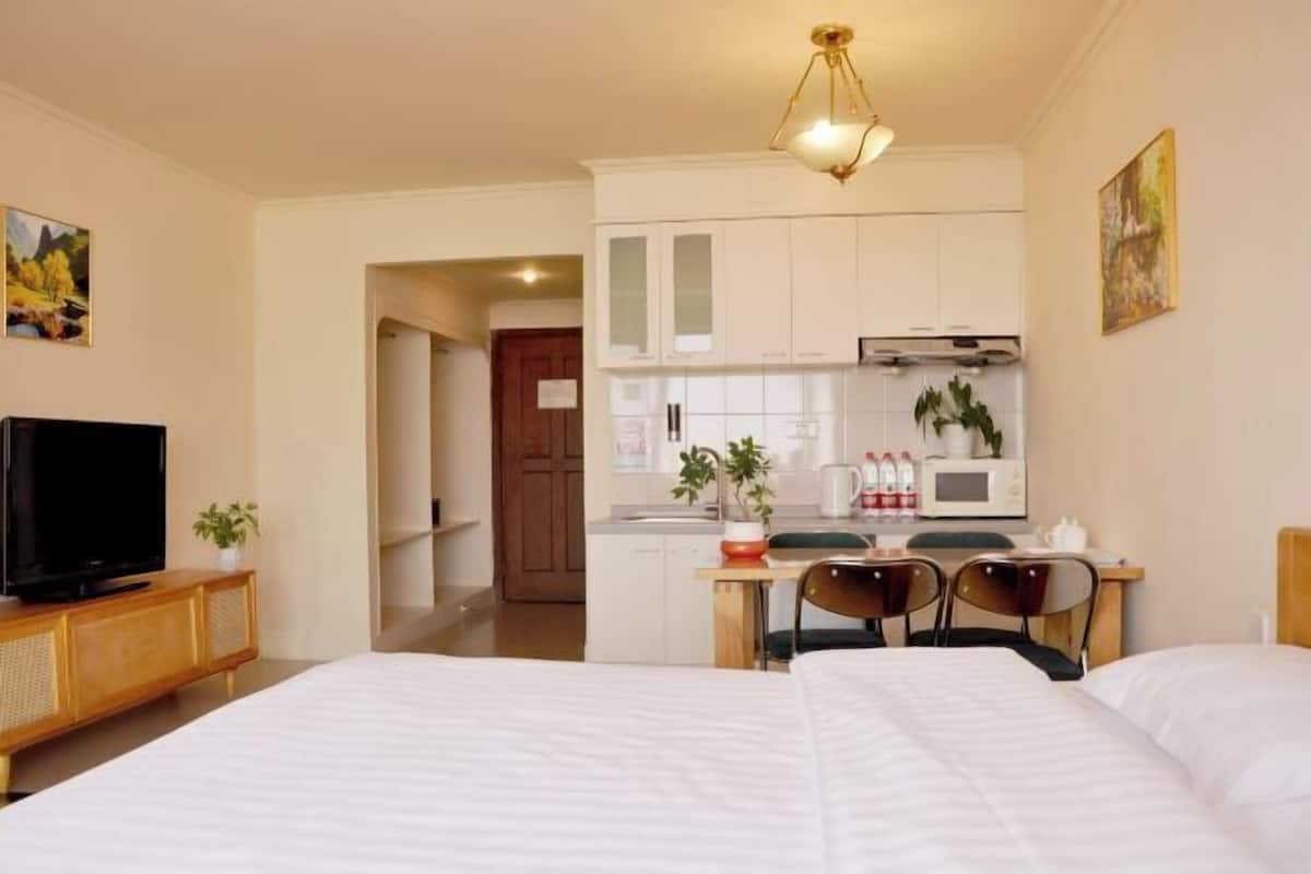 Een hotelkamer met een bed, een televisie, een kitchenette en een eethoek.