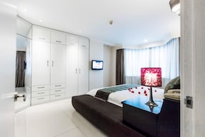 Ein modernes Schlafzimmer mit Bett, Fernseher und Kleiderschrank.