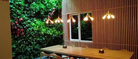 A dining area with a wooden table and chairs, a window, and a wall with vertical slats.