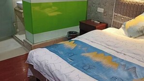 Une chambre à coucher comprenant un lit, une table de chevet, une commode, un mur orné d’un motif floral et un mur vert et blanc.