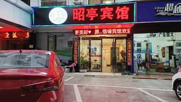 Un escaparate con un letrero llamativo, un coche rojo estacionado adelante y un paso de peatones.
