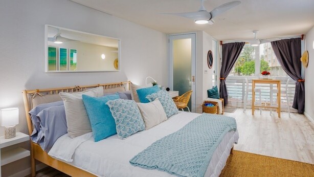 A bedroom with a bed, bedside table, and a view of the outside.