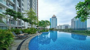 A modern hotel with a swimming pool, lounge chairs, and a view of surrounding buildings. - Morich Suite Antasari (Jakarta)