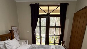 Une chambre avec deux lits, une armoire en bois, une table de chevet et une fenêtre avec des rideaux.