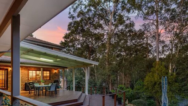 Un espace extérieur abrité, doté d’une table et de chaises, et entouré d’une végétation luxuriante et d’arbres.
