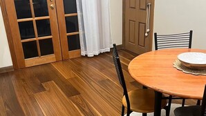 Un coin repas avec une table ronde en bois, quatre chaises et un tapis blanc.