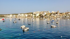 Un paisaje urbano costero con numerosos barcos amarrados en un puerto, rodeado de edificios densamente agrupados.